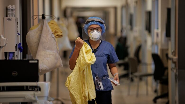 A nurse gowns up before attending to a patient in the intensive care unit of Humber River Hospital, in Toronto, on Jan. 25, 2022.