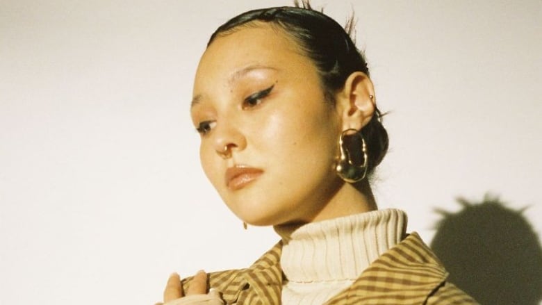 A close-up shot of a woman sporting a septum piercing and long earrings.