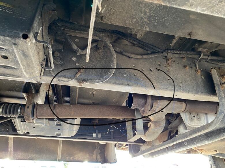 the underside of a vehicle showing the exhaust system and where a catalytic converter has been cut out