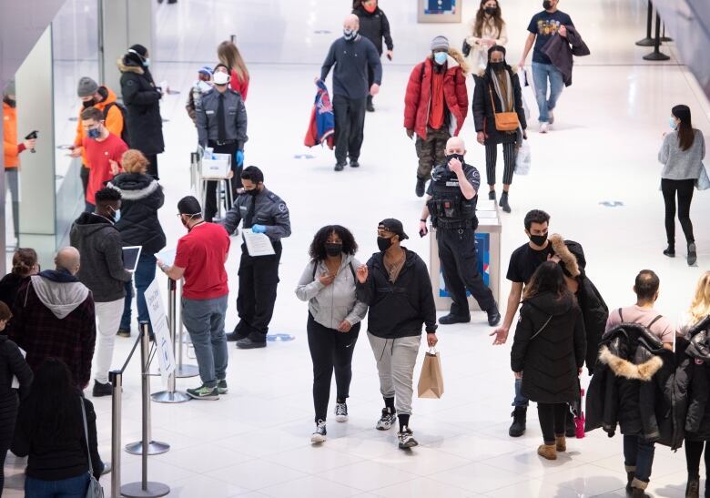 People in a mall on Christmas Eve. All are wearing COVID face masks.