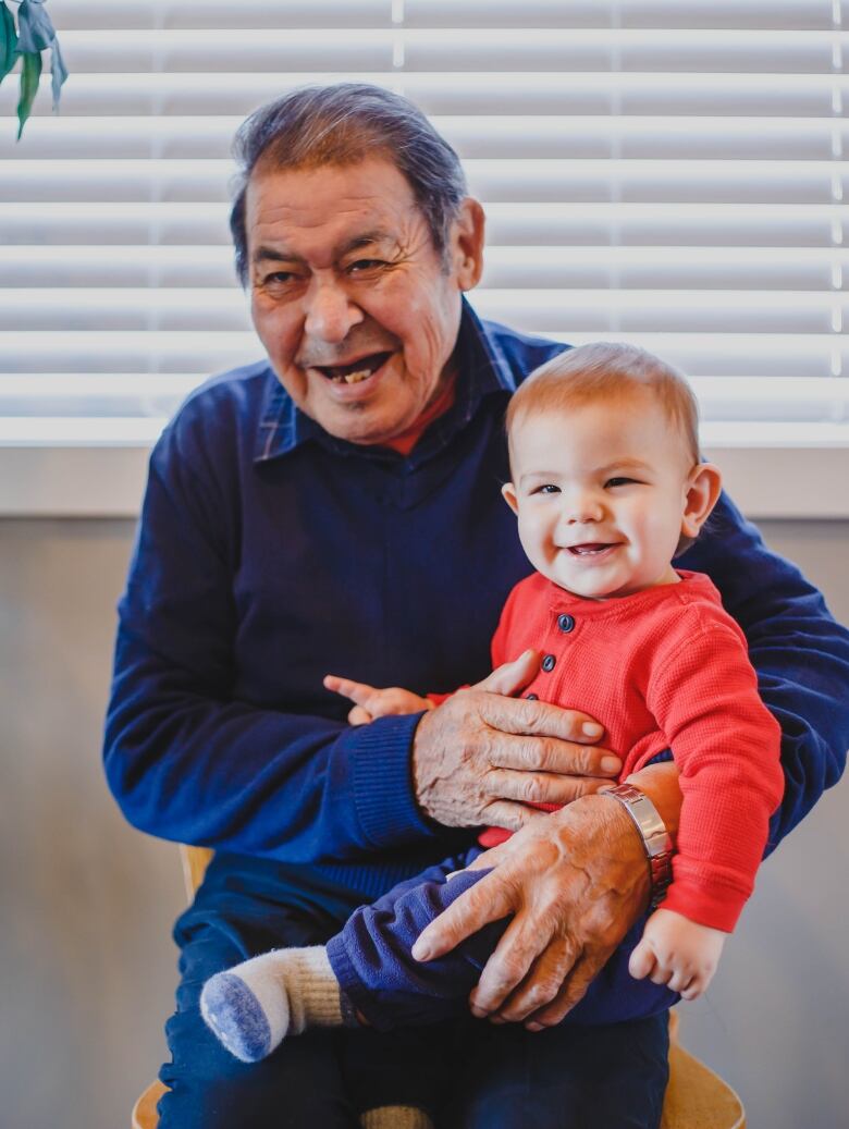 A grandfather and his grandson pose for a picture. 