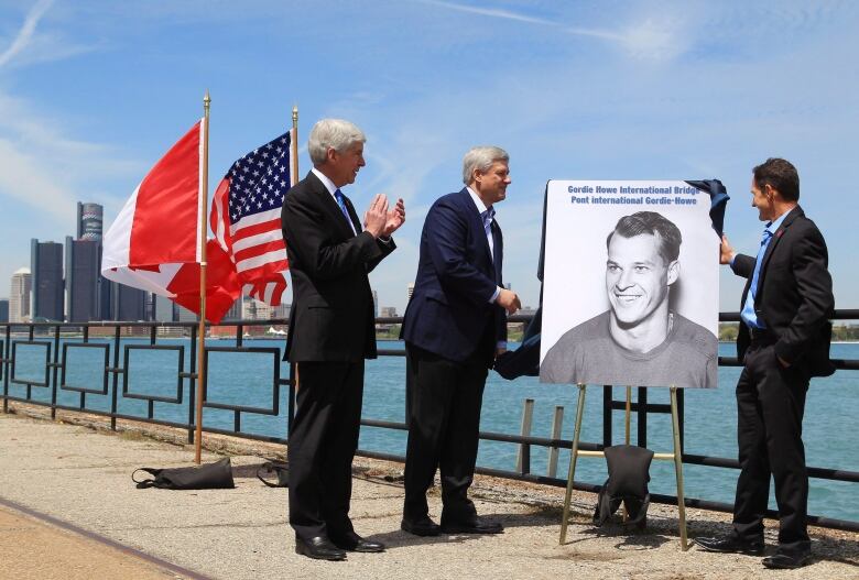 Michigan Governor Rick Snyder (left to right), Prime Minister Stephen Harper and Murray Howe, Gordie Howe's son, announce that the Detroit River International Crossing will be named the Gordie Howe International Bridge, on the waterfront, in Windsor, Ontario, Thursday May 14, 2015. THE CANADIAN PRESS/Dave Chidley