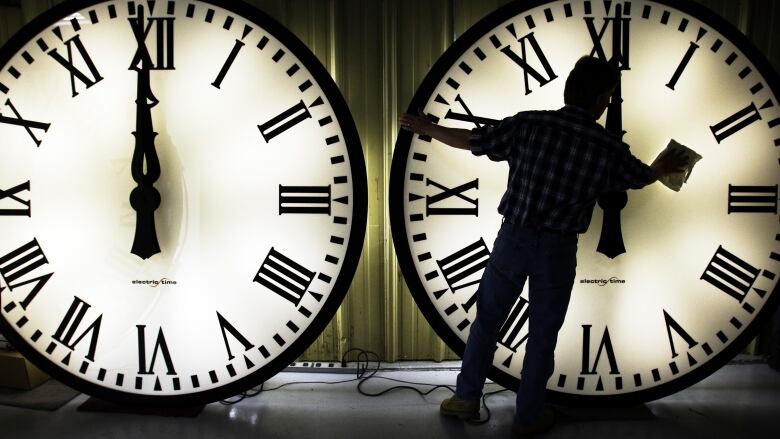 A worker in Medfield, Mass., wipes a tower clock in March 2009 before the start of daylight savings time.