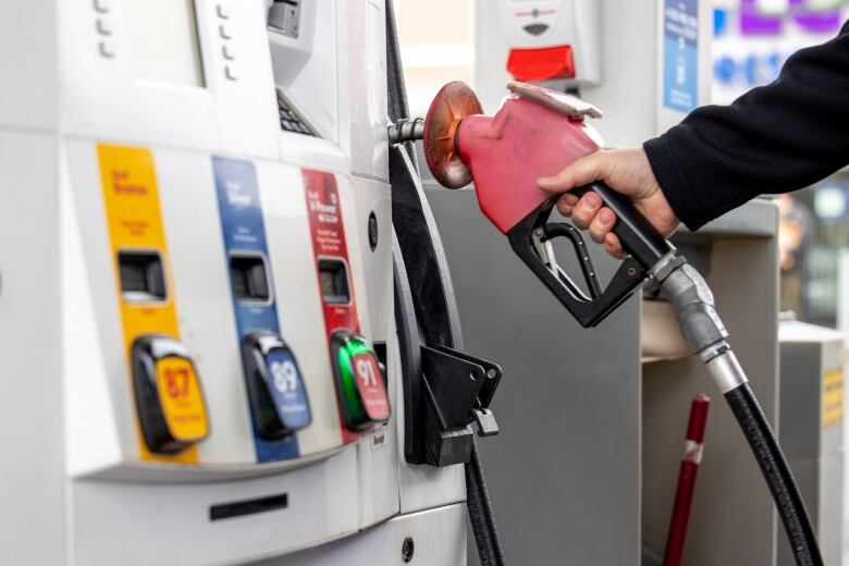 A gas pump with a hand on the handle