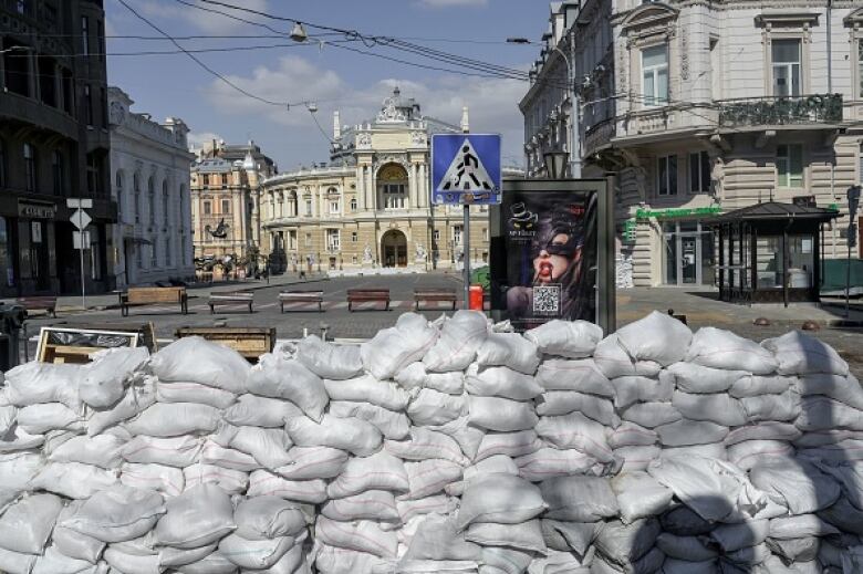 A barricade of sandbags sits on a city street in front of several buildings.