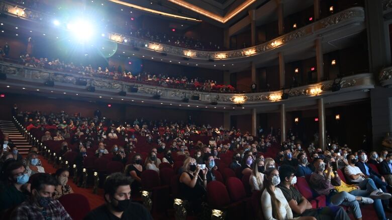 A masked audience attends a movie screening at Toronto's Princess of Wales Theatre.