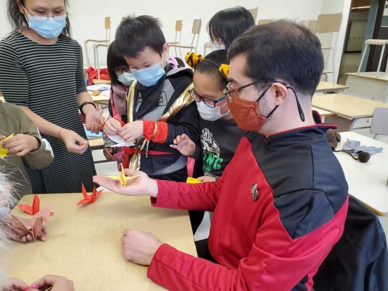 CBC journalist Matt D'Amours gets a paper-folding lesson from students at the Brossard Chinese School.