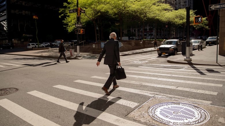 Man in business suit crossing the street at a crosswalk.