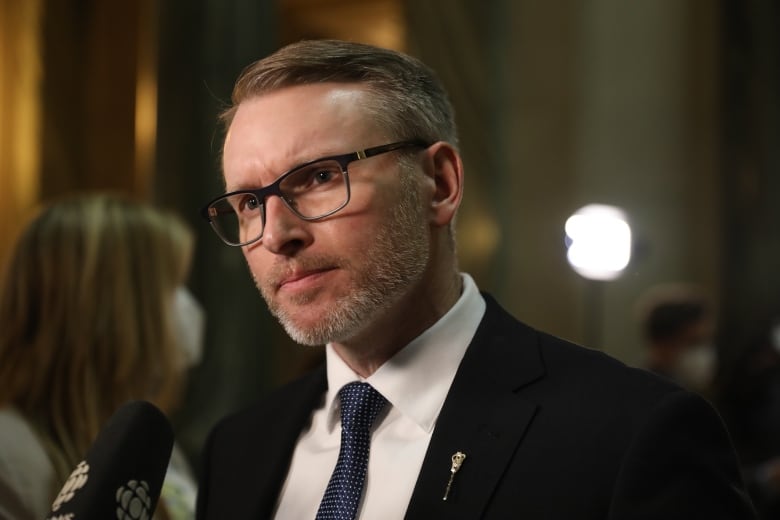 A man wearing glasses and wearing a dark suit with a dotted tie