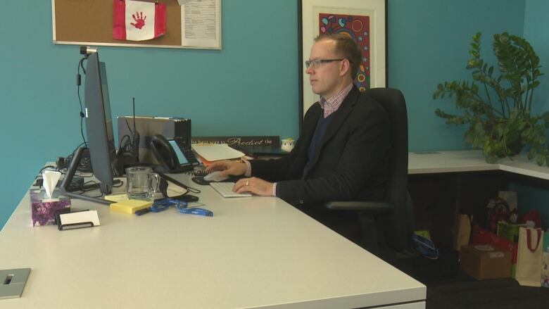 Jason Reynar sits at a desk.