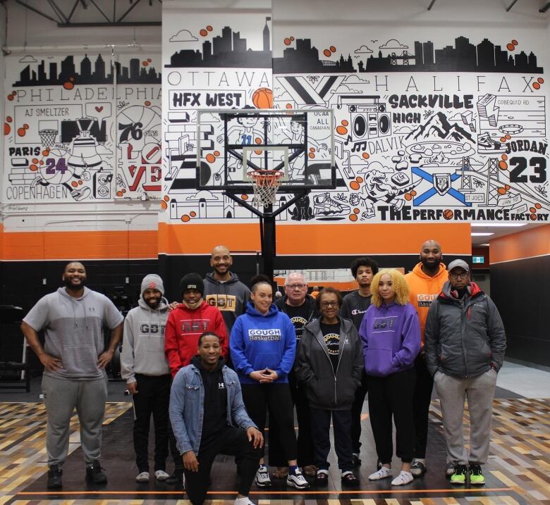 A group of people stand for a photo in front of a basketball net