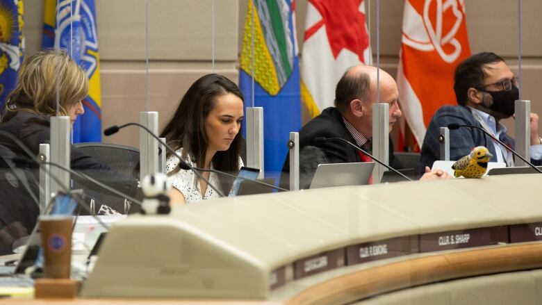 Men and women sit as the desks in the Calgary Council chambers.