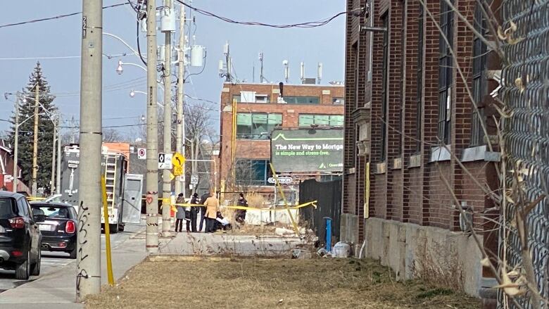 A crime scene on a street with caution tape surrounding it.