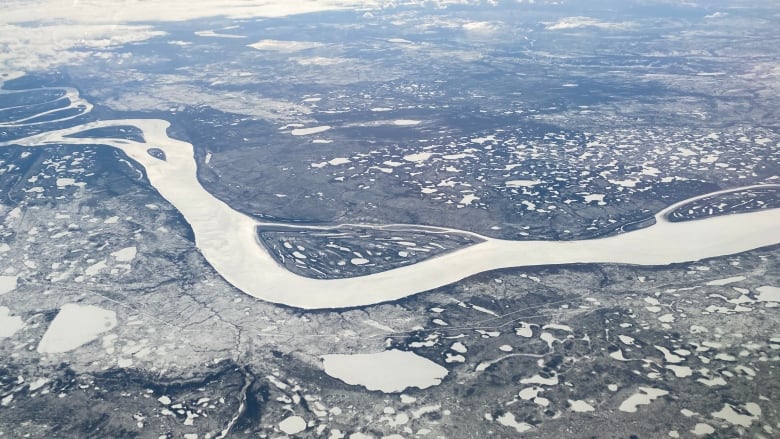 Aerial view of a white, frozen river winding through a snowy landscape.