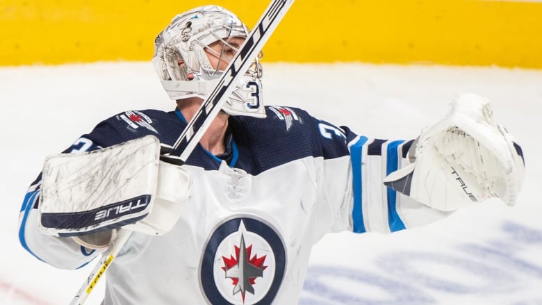 Men's goalie raises his stick in the air and extends his left arm in celebration of a victory.