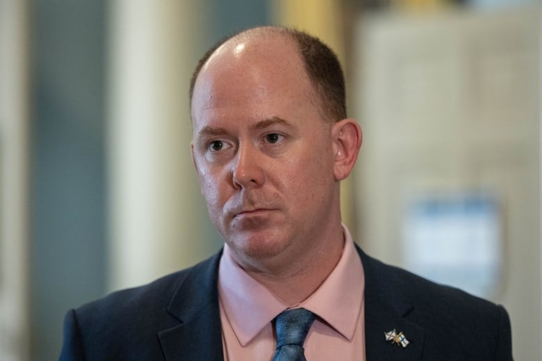 A man in a suit and tie stands inside a building.