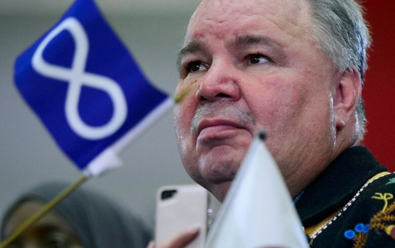 A politician with a miniature Mtis flag on his desk beside him.