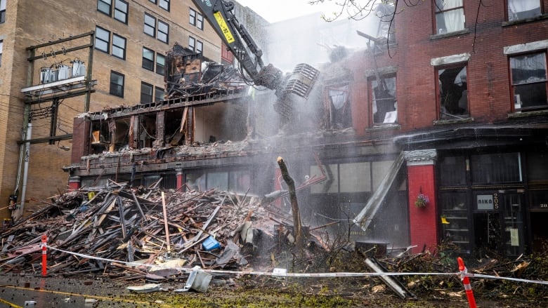 A burned down building with dust rising from it.