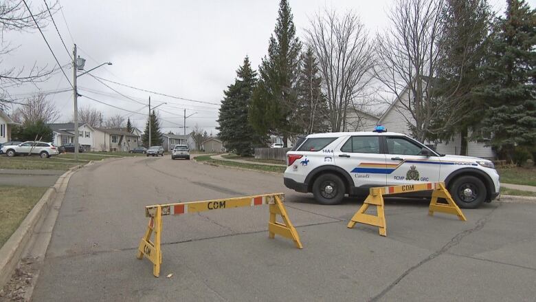 Yellow barriers block and an RCMP SUV block a street. 