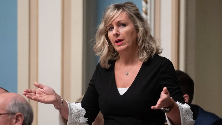 blonde woman in black and white top speaks at Quebec's National Assembly