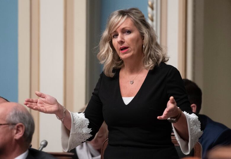 blonde woman in black and white top speaks at Quebec's National Assembly