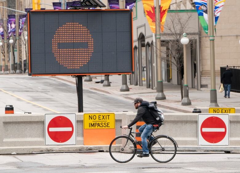 A man cycles along a blocked off road.