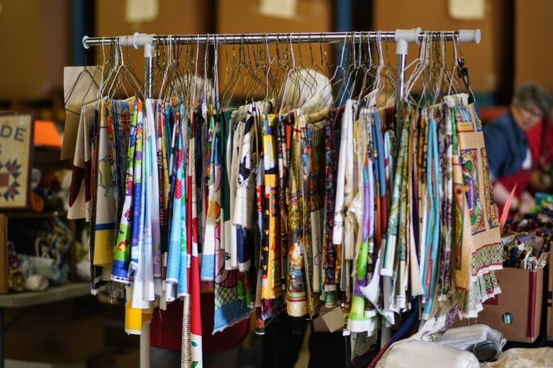 A clothing rack holds hangers filled with different small fabric samples. 