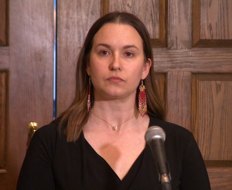 A woman with brown hair wearing a black dress.