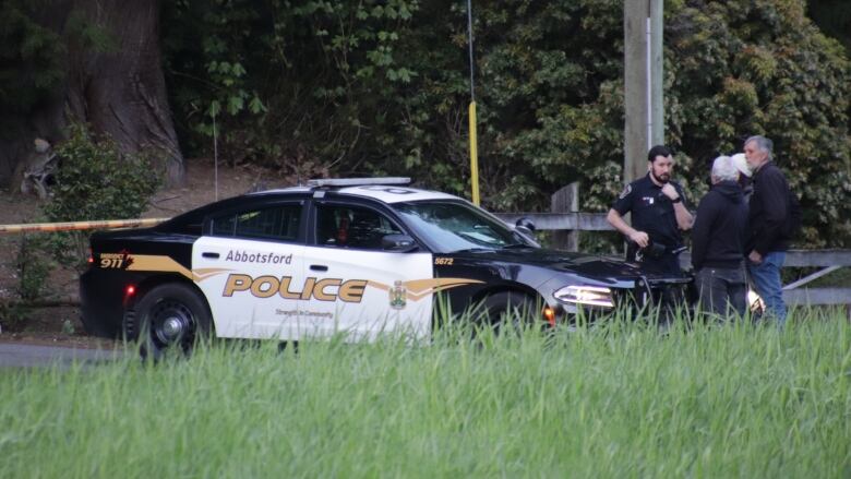 Police officers are seen at the front of a police car.