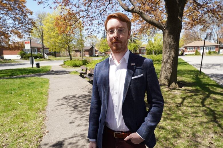 man in blue blazer posing at a park