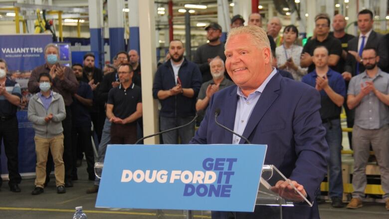 A man in a blue shit stands at a podium