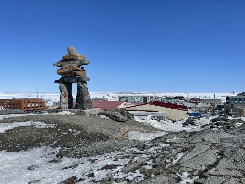 Inuksuk on rocks over village.