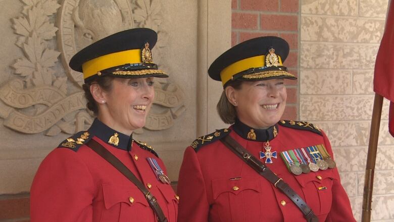 Two smiling women in red RCMP serges stand beside each other.