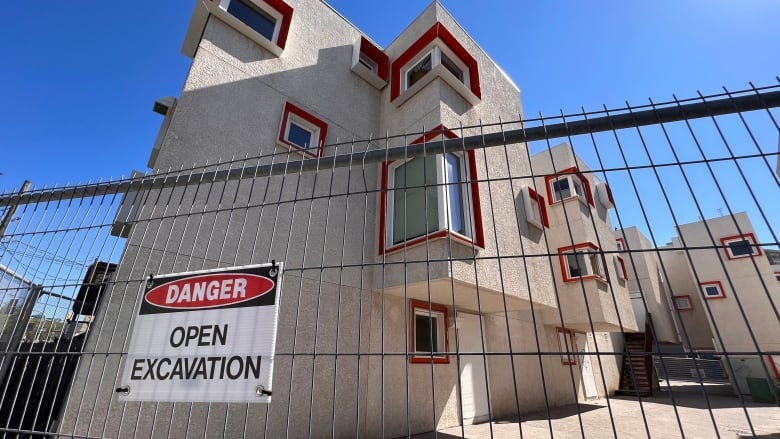 A security fence in front of a beige building.