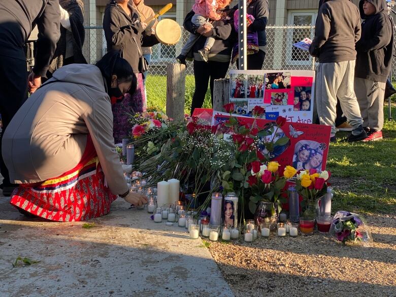 A person puts down a candle at a vigil.