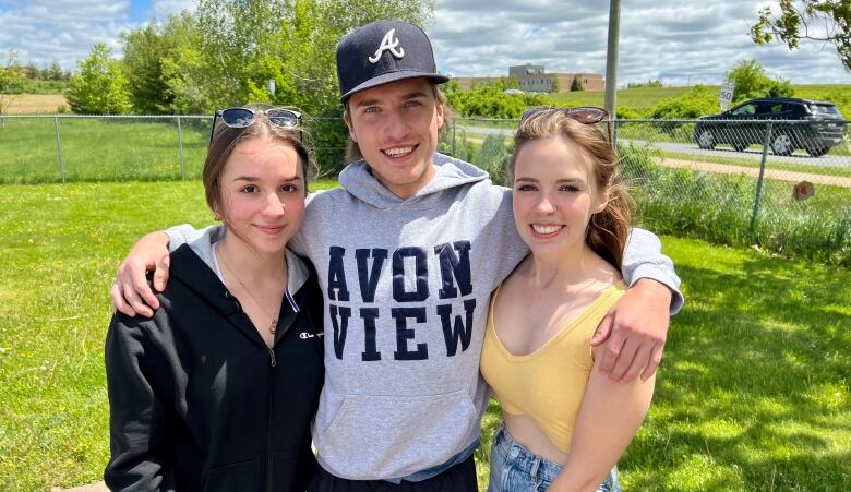 Three students of Avon View High School are seen smiling outside together. 