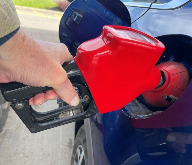 A hand holds a red gas pump.