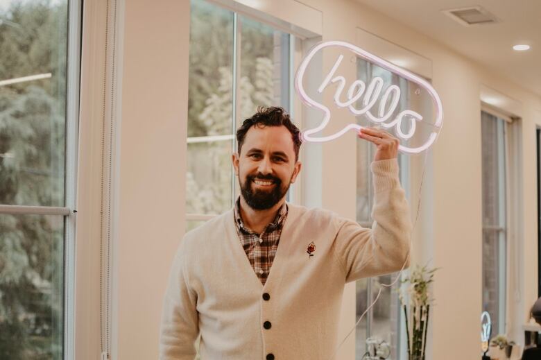 A man with a beard holds a speech bubble saying 