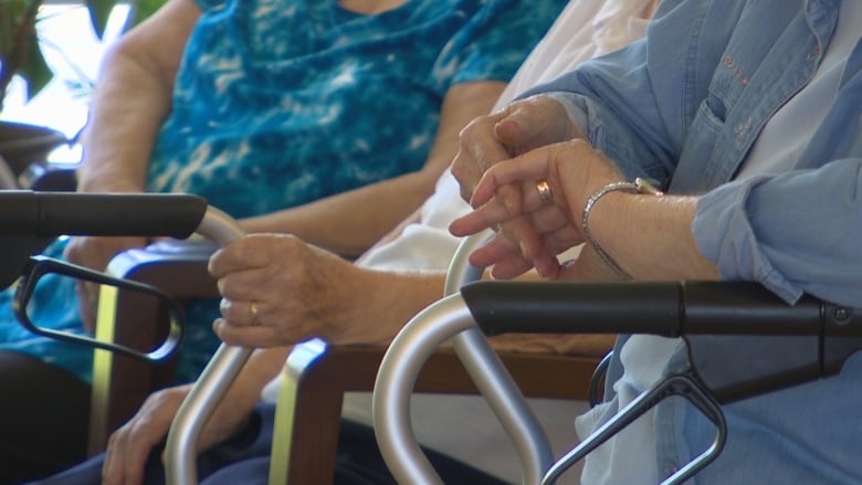 Hands are wrists are visible near armrests and walkers.