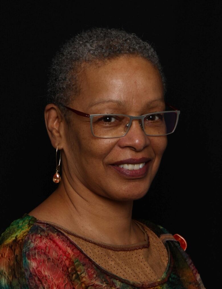 A Black woman with short hair wearing glasses