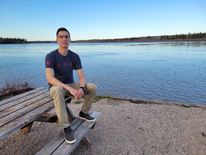 A man sits on a picnic table. 