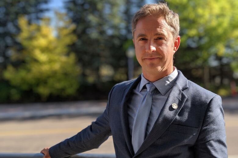 A smiling man in a suit standing outside