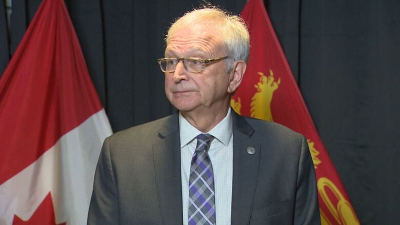 A man stands in front of flags.