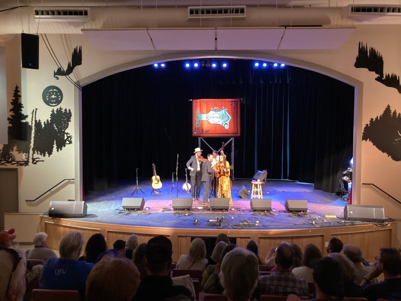 A bluegrass band performs on an auditorium stage.