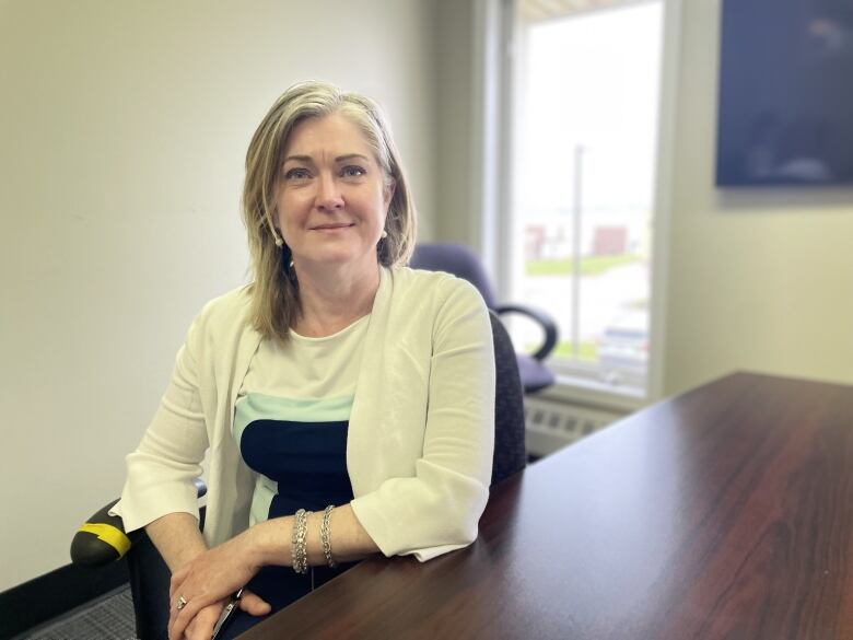 Woman sits at desk. 