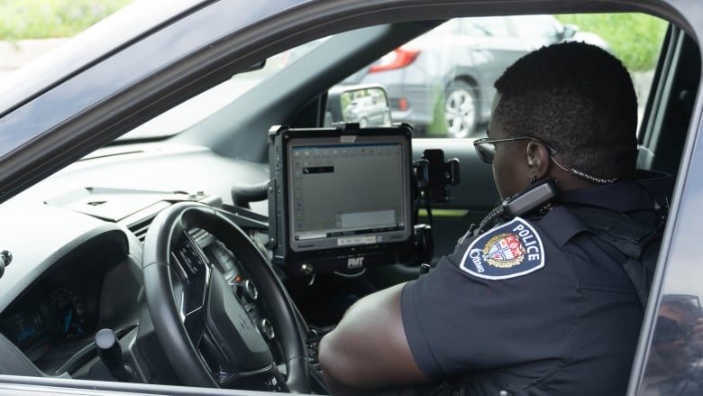 An Ottawa police officer uses the in-vehicle computer near their Elgin Street headquarters in June 2022.