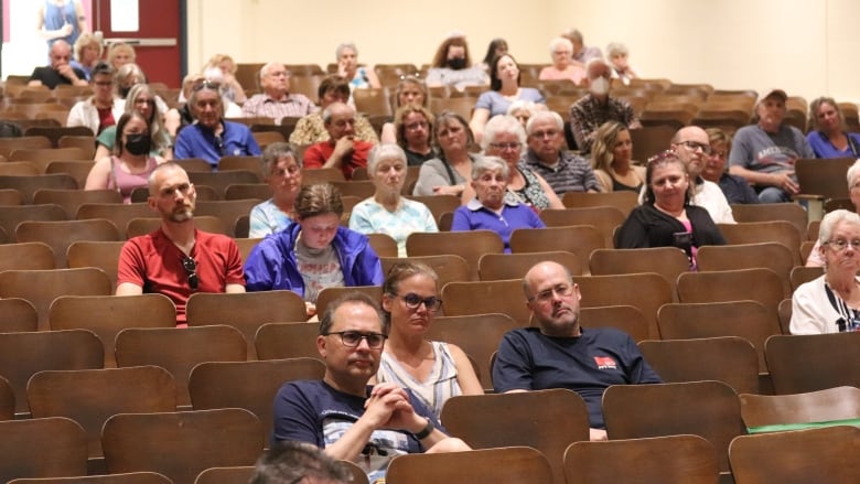 People seated around an auditorium at Harrison Trimble High School in Moncton.