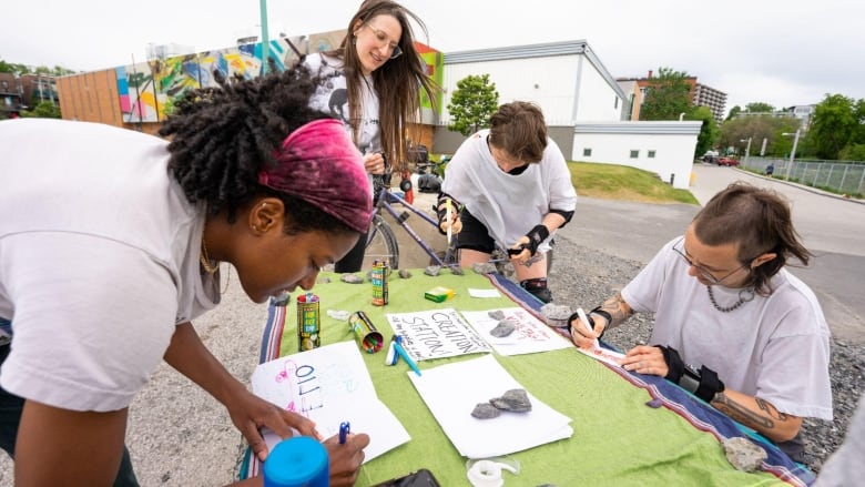 A group of young people use markers on pieces of paper outdoors in Montreal.