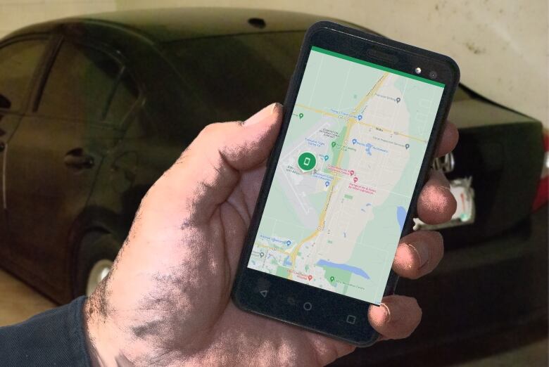 A hand holding a cellphone with a car in the background.