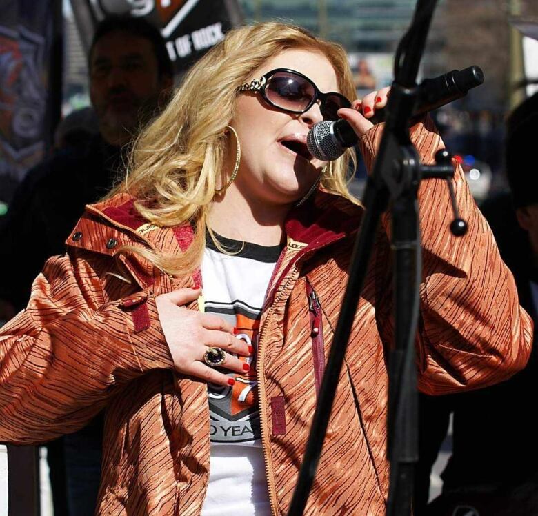 A woman is seen singing into a microphone.